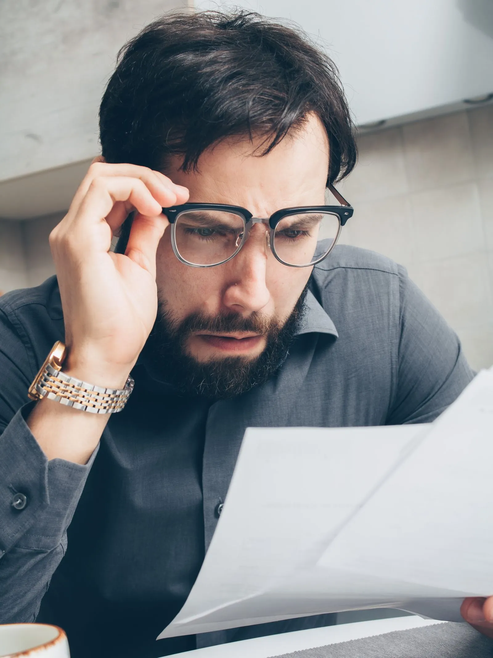 A worried man examines financial paperwork.