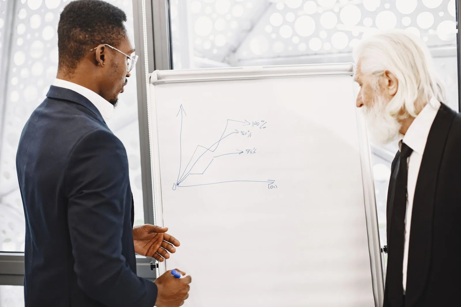 Two colleagues discuss a chart during a business meeting.